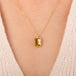 Gold necklace featuring a citrine gemstone worn on a person's neck.