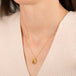 Gold necklace featuring a rectangular citrine gemstone, worn on a person's neck.