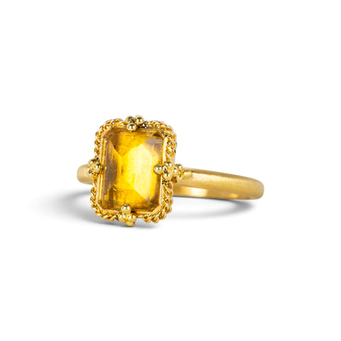 Gold ring featuring a citrine stone set in an 18k gold bezel, shown against a white background.