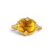 A gold ring featuring a citrine gemstone, set against a white backdrop. 