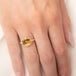 A gold ring featuring a citrine gemstone, worn on a finger.
