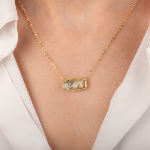 Gold necklace featuring a dendritic quartz stone on a model's neck.