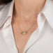 Gold necklace featuring a dendritic quartz stone on a model's neck.
