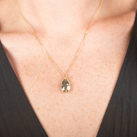 Necklace with a teardrop-shaped diamond set in a handcrafted gold bezel on a person