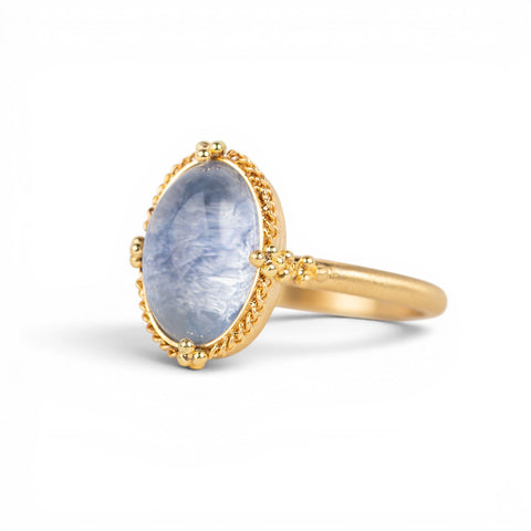 Gold ring with a blue dumortierite stone on a white background