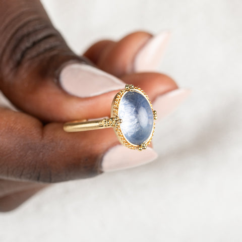 Gold ring with a blue dumortierite stone held in hand
