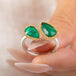 A gold and silver ring featuring two emerald stones held in hand