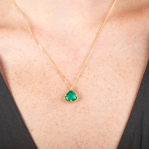 Handmade necklace with a one-of-a-kind emerald gemstone set in a handmade gold bezel on a person's neck.