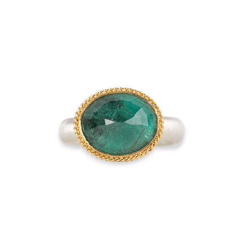 An oval emerald gemstone ring set in a gold bezel, with a sterling silver band, shown against a plain white background.