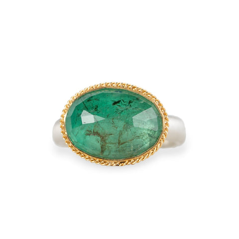 A gold and silver ring featuring an emerald stone, shown against a white background.