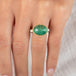 A gold and silver ring featuring an emerald stone, worn on a person's finger.