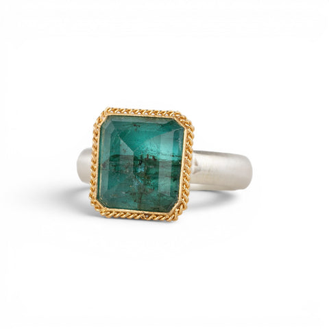 A square emerald-cut green gemstone ring with a gold bezel and sterling silver band, shown on a white background.