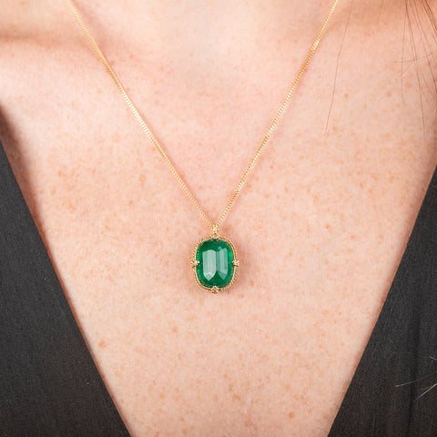 Handcrafted gold necklace with an emerald gemstone pendant on a model's neck.
