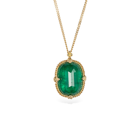 Handcrafted gold necklace with an emerald gemstone pendant on a white background.