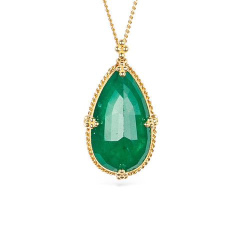 Emerald teardrop pendant with handcrafted gold setting on a white background