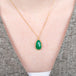 Gold necklace with Emerald teardrop worn by a model