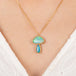 Boulder opal pendant necklace in mushroom design on a gold chain against a person in a white top