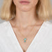 Boulder opal pendant necklace in mushroom design on a gold chain against a person in a white top