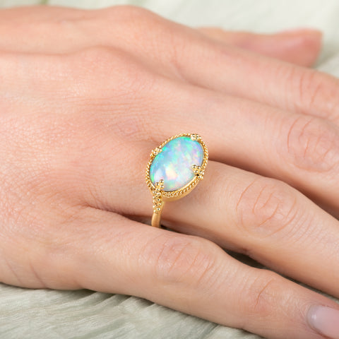 Gold ring with an opal stone on a hand