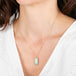 Gold necklace with an Ethiopian opal pendant worn by a person against a white background