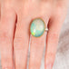 Hand wearing an Ethiopian opal ring with a gold bezel and sterling silver band