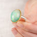Hand holding an ethiopian opal ring with a gold bezel and sterling silver band