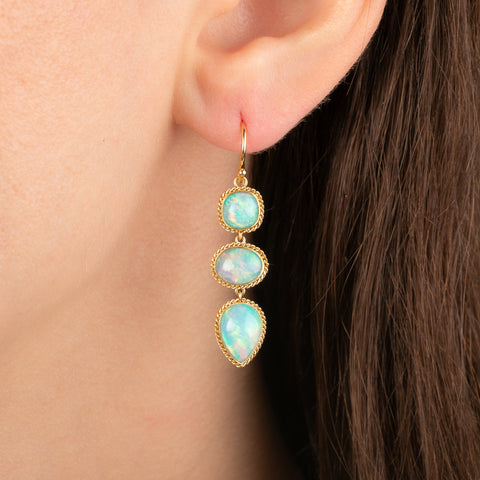 A close up of an ear wearing an ethiopian opal earring, shown on a model.