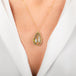 A teardrop-shaped Ethiopian Opal necklace set in a gold bezel worn on a person's neck