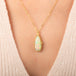 Gold necklace featuring an Ethiopian opal gemstone set in a handcrafted 18k gold bezel and strung from a matching gold chain, worn on a person's neck.