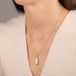 Gold necklace featuring an Ethiopian opal gemstone set in a handcrafted 18k gold bezel and strung from a matching gold chain, worn on a person's neck.