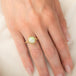 Gold ring featuring a circular Ethiopian opal gemstone set in a handmade 18k gold bezel, worn on a person's finger.
