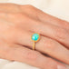 Gold ring featuring a vibrant Ethiopian opal stone, worn on a person's finger.