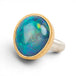 Ring with a large opal stone set in a gold bezel with a silver band on a white background
