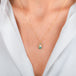 A gold teardrop-shaped Ethiopian Opal necklace worn on a person's neck.
