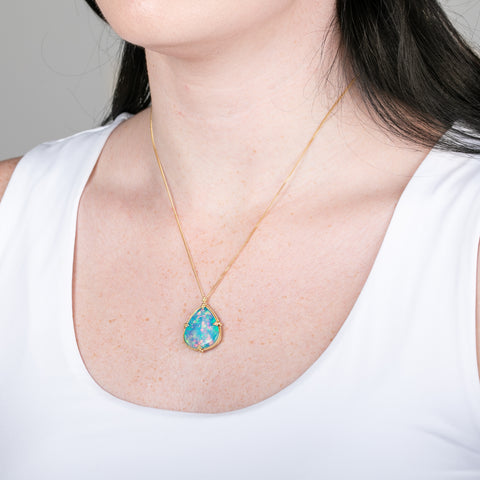 Ethiopian opal pendant necklace with gold setting on a person
