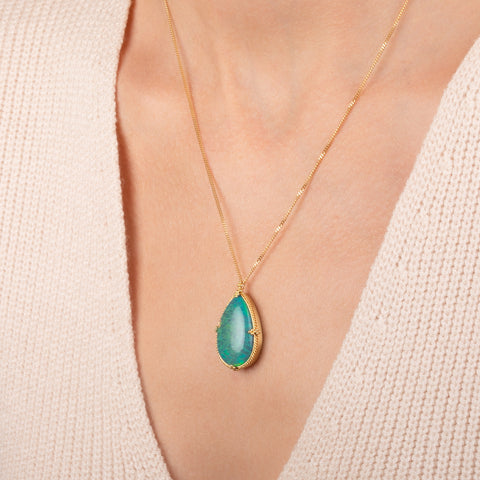 Handcrafted gold necklace featuring a large, teardrop-shaped Ethiopian opal gemstone set in an 18k gold bezel with a matching gold chain, shown worn on a person's neck.