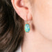 Gold earring with ethiopian opal stone worn by a person