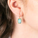 Gold earring with ethiopian opal gemstone worn by a person