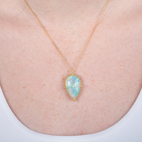 Ethiopian opal pendant necklace with 18k gold bezel on a person