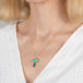 Gold necklace with a mushroom pendant featuring an emerald and opal stone on a person