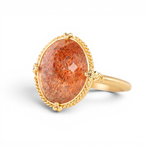 Gold ring with a sunstone stone on a white background