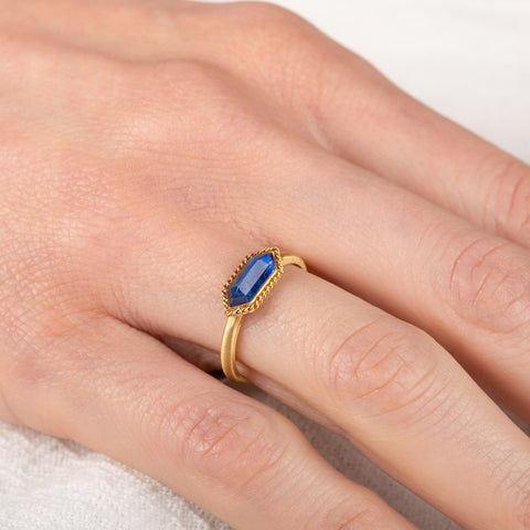 Gold ring with a moonstone on a hand against a neutral background