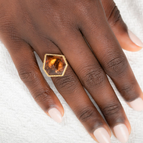 Ring with a tourmaline gemstone on a hand against a white background