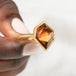 Ring with a tourmaline gemstone held in hand against a white background