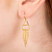 Gold earrings featuring moonstones and gold chain tassels, shown worn in a person's ear.