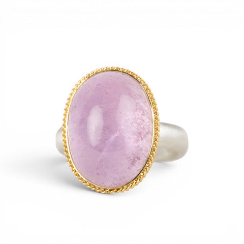 A ring featuring a large oval kunzite stone, set in a gold textured bezel with a sterling silver band.