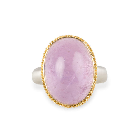 A ring featuring a large oval kunzite stone, set in a gold textured bezel with a sterling silver band.
