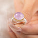 A gold and silver ring featuring a pink kunzite stone, held in hand.