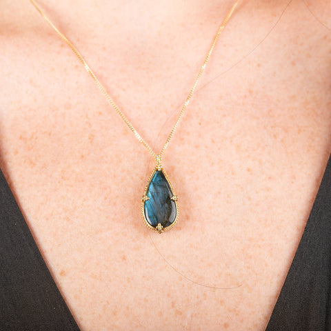 Necklace with a teardrop-shaped labradorite pendant on a person's neck.