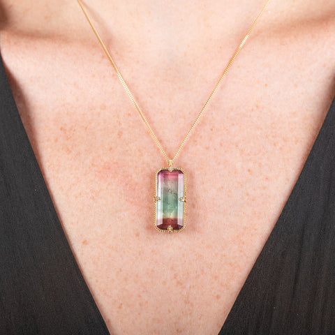 Handmade necklace with a watermelon tourmaline gemstone set in a gold bezel on a person
